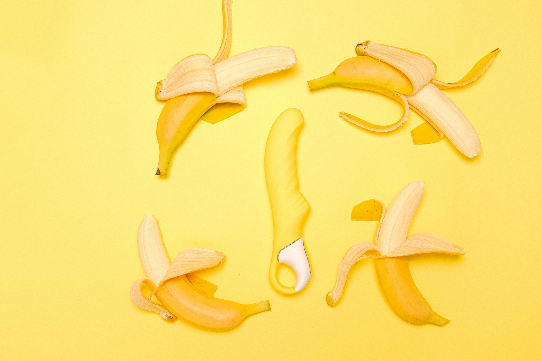 Ein gelber Lemon-Vibrator umgeben von geschälten Zitronen auf gelbem Hintergrund