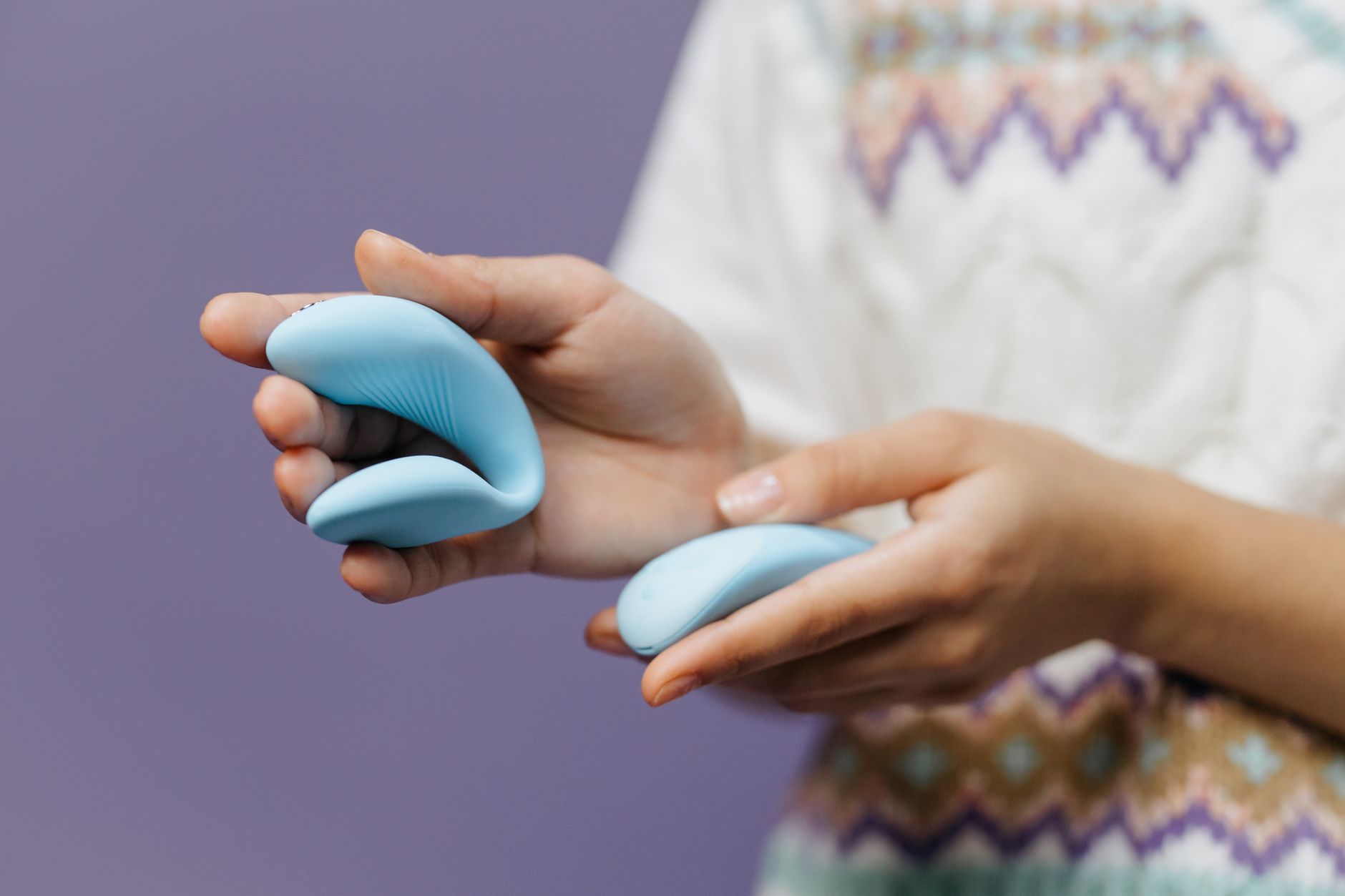 Nahaufnahme von Händen, die einen eleganten blauen Vibrator halten, Symbol für Selbstbestimmung und Heilung