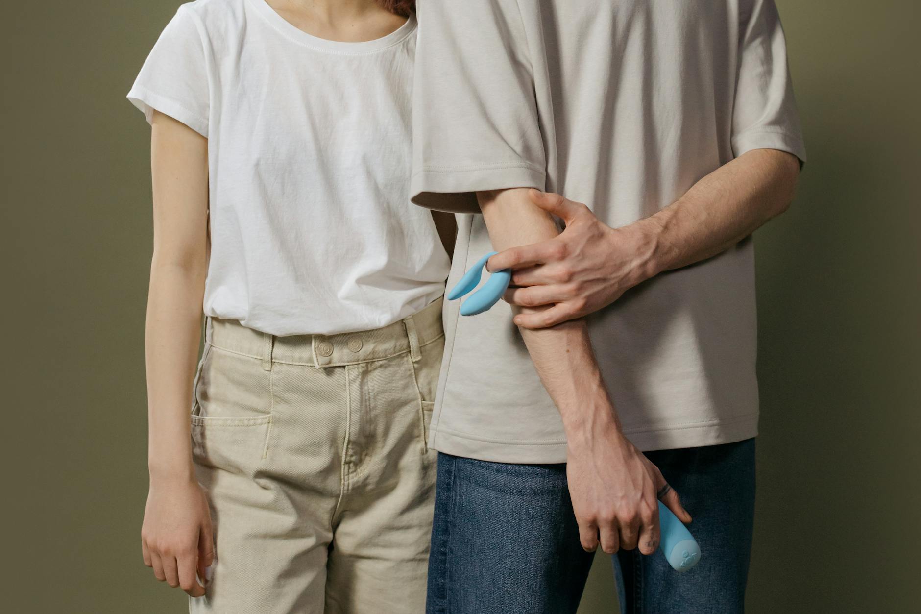 A hand holding an orange vibrator against a minimalistic purple backdrop, symbolizing sensuality and recovery.