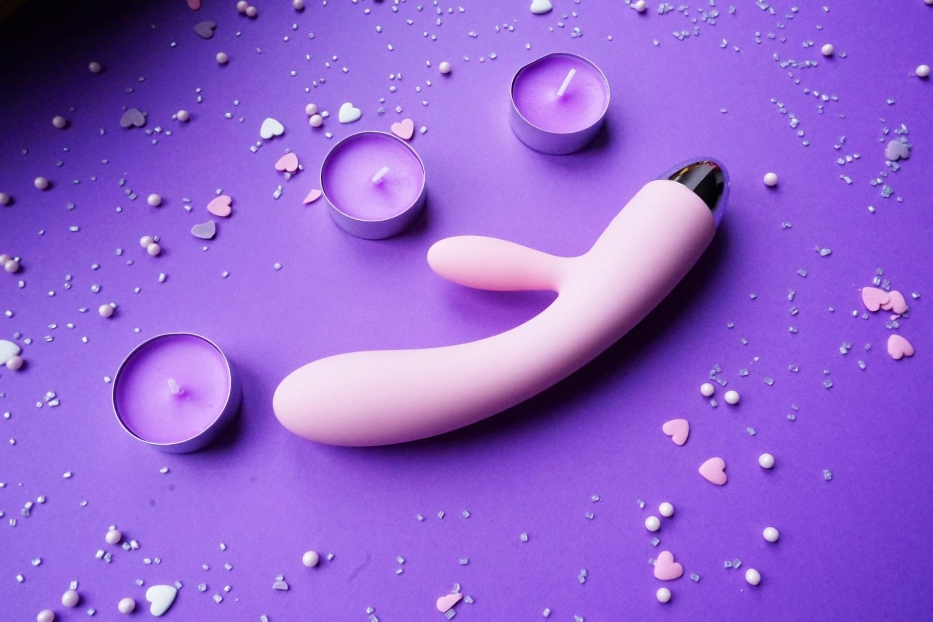 A young couple standing together indoors, holding a blue vibrator, symbolizing modern intimacy and partnership during sexual challenges.